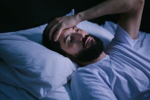 Frustrated man lying awake in bed